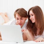 happy couple with a laptop on internet in bed