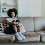 Sad young woman looking away in the living room at home