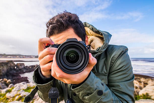 COMPRENDRE L'OUVERTURE ET LA VITESSE D'OBTURATION EN PHOTOGRAPHIE 4 A young man using a DSLR camera at the sea