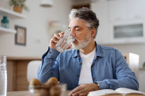 HYDRATATION ET PRODUCTIVITÉ : POURQUOI BOIRE DE L'EAU CHANGE TOUT 6 Man drinking water in kitchen background. People and healthy lif