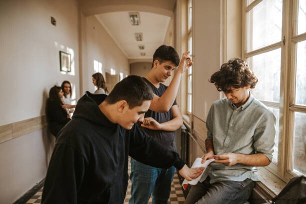 L'EFFET SPECTATEUR : POURQUOI PERSONNE N'AIDE QUAND IL Y A TROP DE MONDE AUTOUR 3 Boys bullying classmate in the school corridor while girls watching