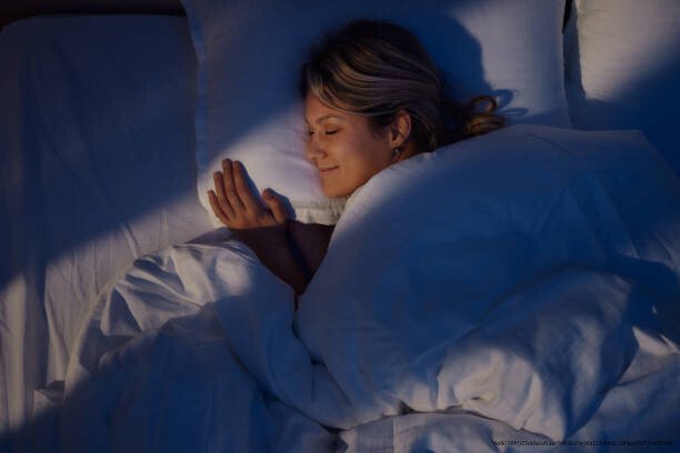 POURQUOI LES RÊVES HUMAINS RESTENT LE DERNIER MYSTÈRE QUE L'IA NE PEUT PAS REPRODUIRE 3 High angle view of young woman smiling while dreaming in bed at night.