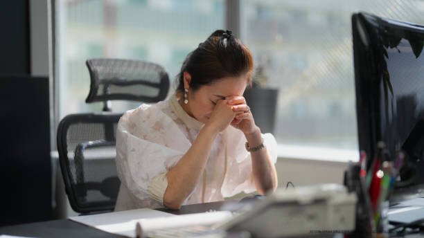 COMMENT LA PRESSION SOCIALE NOUS POUSSE À FAIRE DES CHOSES CONTRE NOS VALEURS PROFONDES 4 A businesswoman is feeling stressed in an office.
