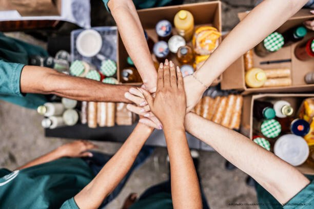 COMMENT LES MILLIARDAIRES UTILISENT LES FONDATIONS CARITATIVES POUR PAYER MOINS D'IMPÔTS 5 Close up of volunteers with hands stacked during donation event outdoors