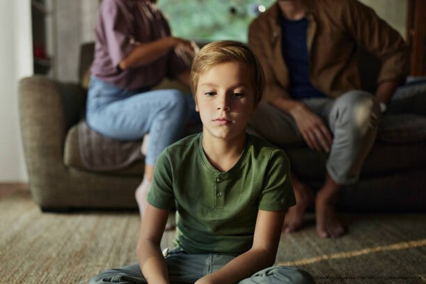 COMMENT SURVIVRE À UN DIVORCE SANS DÉTRUIRE SA VIE ET CELLE DE SES ENFANTS 3 Sad little boy sitting in front of his parents who are arguing at home.