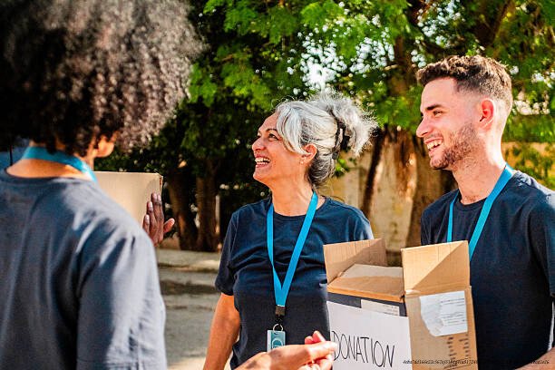 COMMENT LES MILLIARDAIRES UTILISENT LES FONDATIONS CARITATIVES POUR PAYER MOINS D'IMPÔTS 6 Volunteers talking and holding donation boxes outdoors