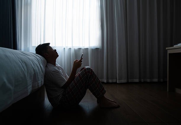 COMMENT LA SOLITUDE EST DEVENUE L'ÉPIDÉMIE INVISIBLE DU 21E SIÈCLE 5 Teenager boy sitting on the bedroom floor and using phone