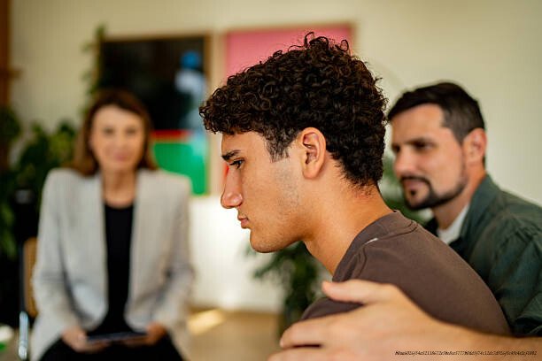 COMMENT RÉSISTER À L'ENVIE DE SE SUICIDER APRÈS UNE DÉCEPTION AMOUREUSE BRUTALE SELON LES EXPERTS EN PSYCHOLOGIE 5 Teenage boy being comforted by father during psychotherapy session