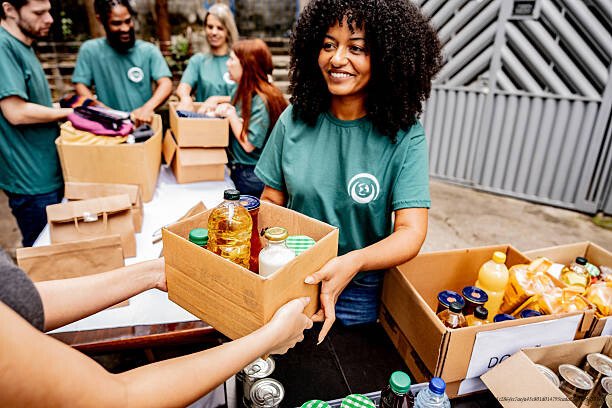 COMMENT LES MILLIARDAIRES UTILISENT LES FONDATIONS CARITATIVES POUR PAYER MOINS D'IMPÔTS 3 Volunteer woman passing donation box outdoors
