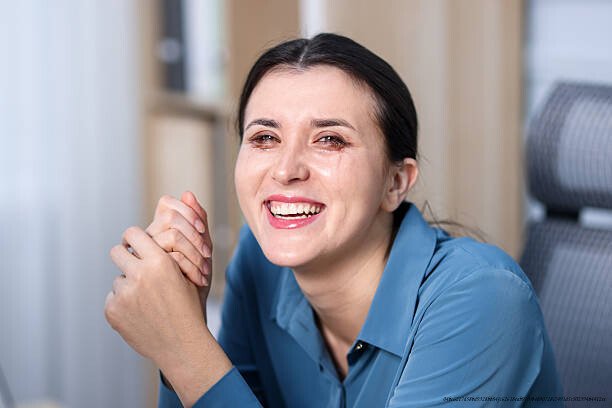 DÉPRESSION : POURQUOI LES GENS QUI SOURIENT LE PLUS SONT SOUVENT LES PLUS TOUCHÉS 3 Young woman laughing through tears at home