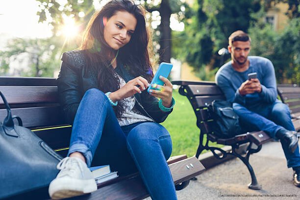 POURQUOI ET COMMENT SORTIR DE LA COURSE À L'AMOUR À TOUT PRIX EN 5 ÉTAPES 5 Teenage couple using smartphones in the city park