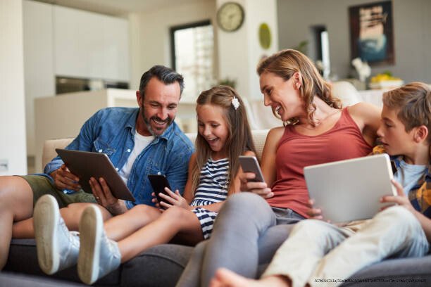 GÉRER LA TECHNOLOGIE EN FAMILLE : ÉTABLIR DES RÈGLES NUMÉRIQUE EN FAMILLE 5 Shot of a happy young family using wireless devices on the sofa at home