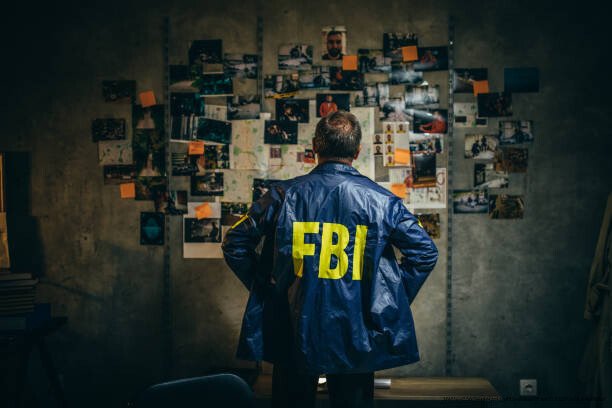 AFFAIRES CRIMINELLES NON RÉSOLUES : ÉNIGMES QUI RESTENT À ÉLUCIDER 6 One man, mature FBI agent working on a case in dark office.