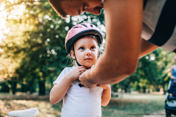 PROTÉGER L'ENFANCE : UN INVESTISSEMENT ESSENTIELLE POUR L'AVENIR DE LA SOCIÉTÉ 3 Father adjusting helmet to his little daughter and she looking at him.