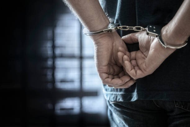 L'ABOLITION DE LA PRISON : UNE PERSPECTIVE INTERNATIONALE 6 Arrested man in handcuffs with handcuffed hands behind back in prison