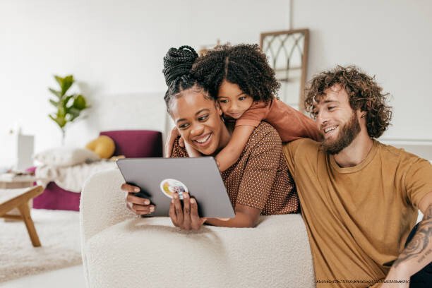 GÉRER LA TECHNOLOGIE EN FAMILLE : ÉTABLIR DES RÈGLES NUMÉRIQUE EN FAMILLE 3 Smiling parents and daughter at home watching online movie together