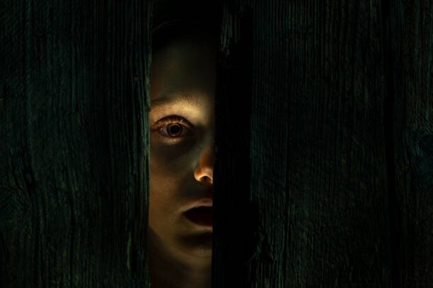 LA SCIENCE ET LES FANTÔMES : UNE EXPLORATION RATIONNELLE DES PHÉNOMÈNES PARANORMAUX 3 Scared girl peeking through a hole