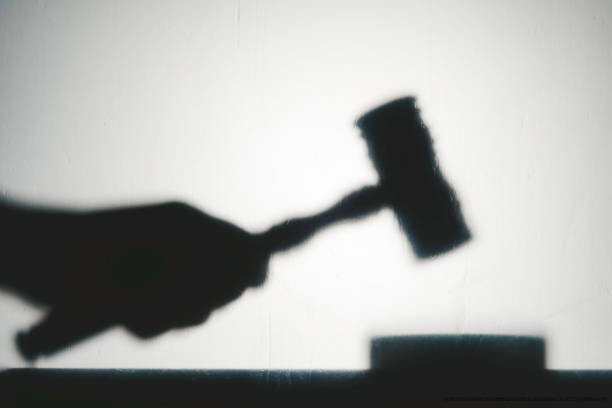 LES INÉGALITÉS DE JUGEMENT : POURQUOI LES FEMMES SONT-ELLES ÉVALUÉES DIFFÉREMMENT DES HOMMES POUR LES MÊME CRIMES 5 Silhouette view of hand with gavel. Representing justice system.