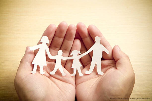 PROTÉGER L'ENFANCE : UN INVESTISSEMENT ESSENTIELLE POUR L'AVENIR DE LA SOCIÉTÉ 4 Paper family in hands with wooden texture background, concept for family love