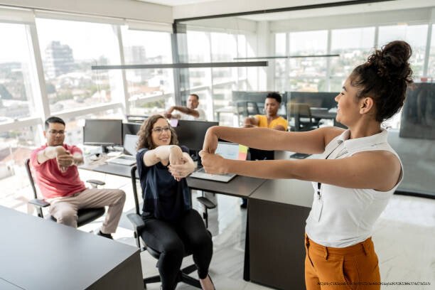 SANTÉ MENTALE AU TRAVAIL : CE QUE LES ENTREPRISES FONT SEMBLANT DE NE PAS VOIR 4 Workers doing stretching exercises before work in a telemarketing office