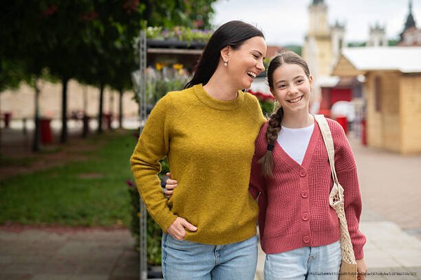 COMMENT ÉTABLIR LE DIALOGUE AVEC UN ADOLESCENT DISTANT SELON LES CONSEILS DES PSYCHOLOGUES 6 Mother embracing daughter while walking in street, tender parenting moment.
