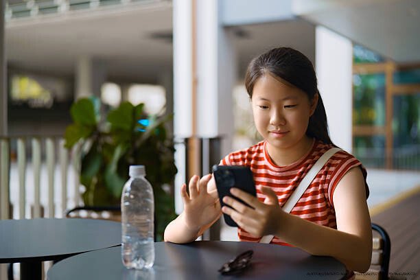 L'ÉVOLUTION DE SINGAPOUR : D'UN PAYS PAUVRE À LA RÉFÉRENCE MONDIALE EN ÉDUCATION EN 5 DÉCENNIES 4 Asian teenage girl using smartphone in coffee shop on city street
