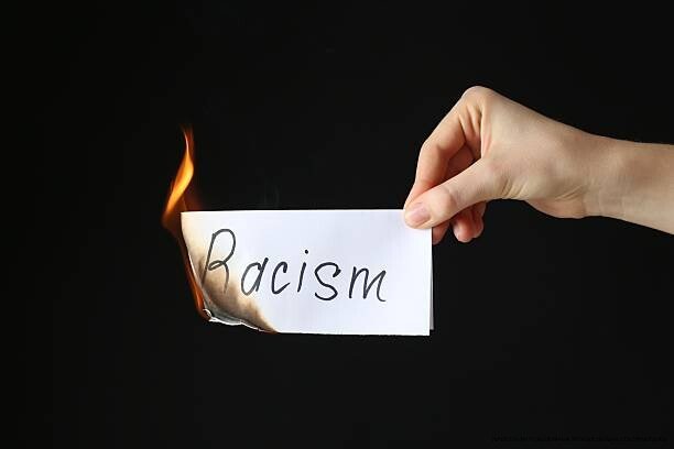 COMMENT LE RACISME QUOTIDIEN CRÉE DES TRAUMATISMES PSYCHOLOGIQUES RÉELS ET DOCUMENTÉS 4 Woman holding burning card with word Racism on black background, closeup