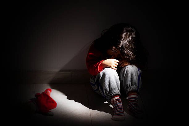L'IMPACT DE L'ENFANCE TRAUMATIQUE SUR LA CRIMINALITÉ ADULTE 4 young girl sitting down alone in the dark.
